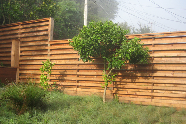 Fence with alternating horizontal slats gives privacy, but allows sunlight to penetrate at an angle.