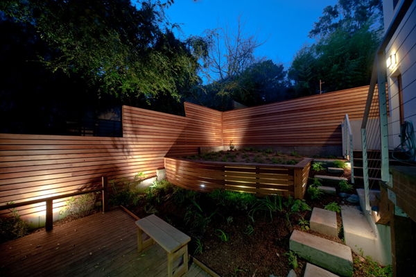 A redwood fence comes alive in the evening with a series of low-voltage lights.