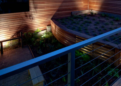 Urban Mood Lighting: Small city garden comes alive at night with light-washed redwood fences and curved retaining walls lit from within.