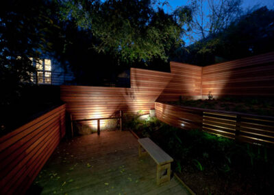 Urban Mood Lighting: Small city garden comes alive at night with light-washed redwood fences and curved retaining walls lit from within.