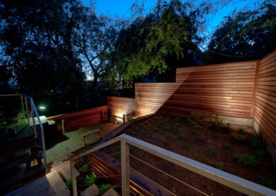 Urban Mood Lighting: Small city garden comes alive at night with light-washed redwood fences and curved retaining walls lit from within.