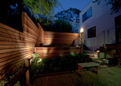 Urban Mood Lighting: Small city garden comes alive at night with light-washed redwood fences and curved retaining walls lit from within.