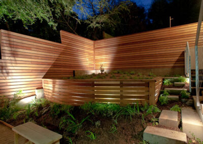 Urban Mood Lighting: Small city garden comes alive at night with light-washed redwood fences and curved retaining walls lit from within.
