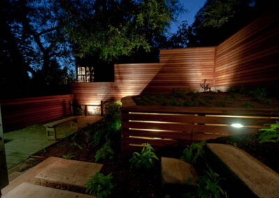 Urban Mood Lighting: Small city garden comes alive at night with light-washed redwood fences and curved retaining walls lit from within.