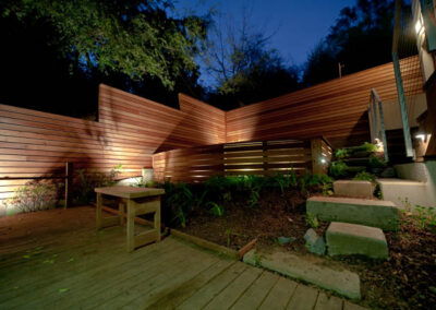 Urban Mood Lighting: Small city garden comes alive at night with light-washed redwood fences and curved retaining walls lit from within.